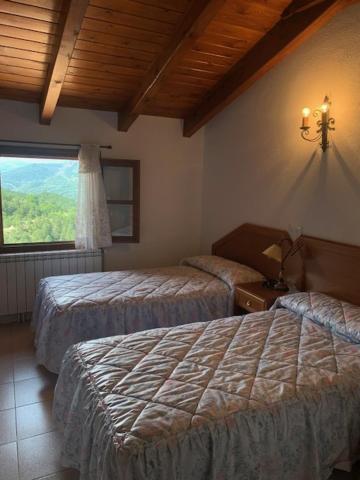 VilallerにあるCasa Enriu-Alojamiento y desayunoのベッド2台と窓が備わるホテルルームです。