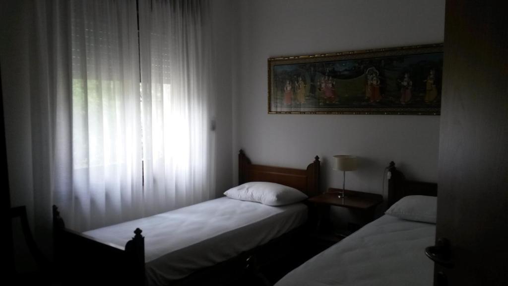 2 Betten in einem kleinen Zimmer mit Fenster in der Unterkunft Casa Betulla in Rovereto