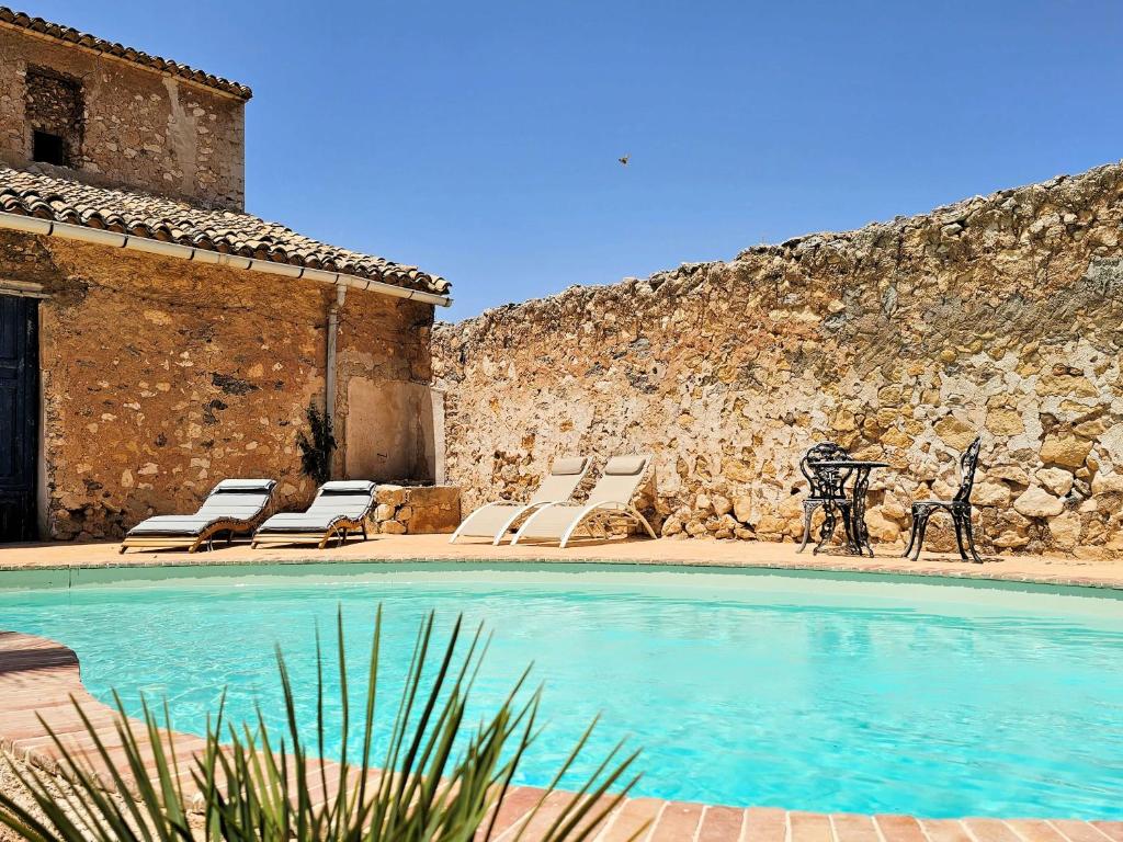 a pool with lounge chairs next to a stone wall at Casa Rodriguillo in Pinoso