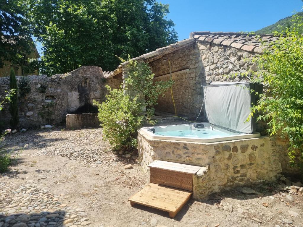 ein Steingebäude mit einer Badewanne im Hof in der Unterkunft Grand Mas Provençal avec jacuzzi in Sisteron