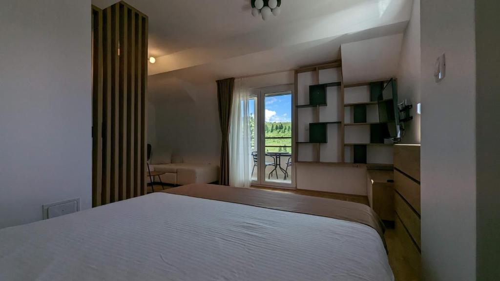 a bedroom with a large white bed and a window at Apartman ANA in Žabljak