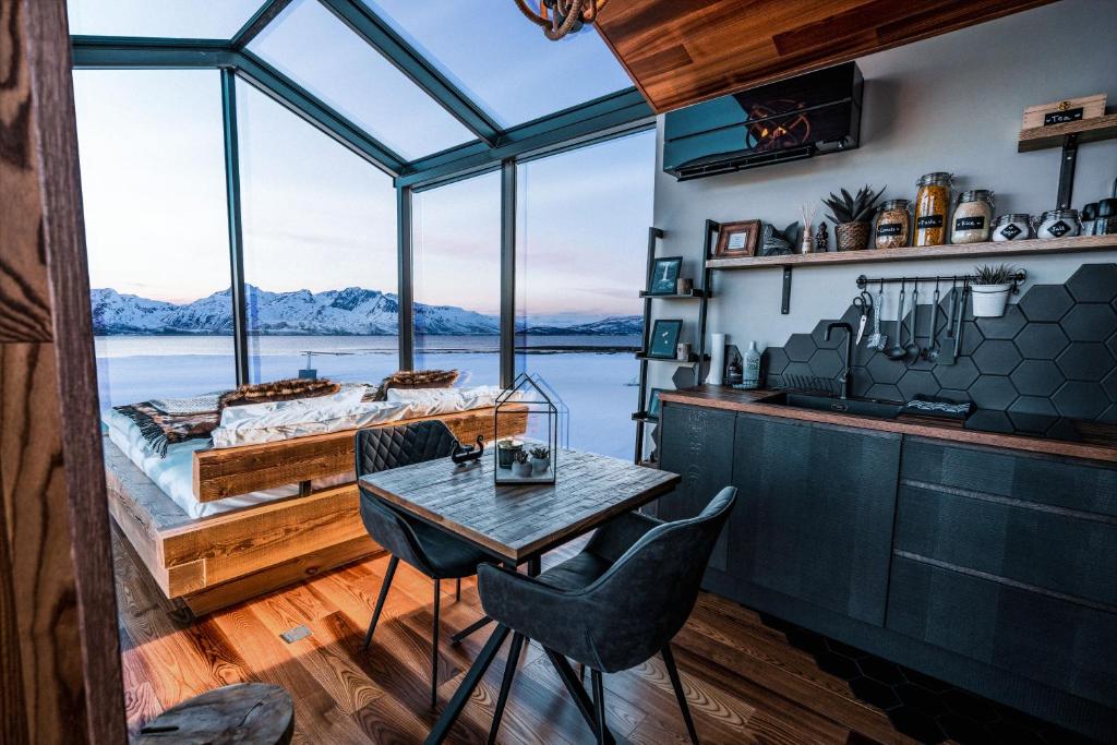 um quarto com uma cama, uma mesa e cadeiras em Aera - Glass cabins em Tromsø