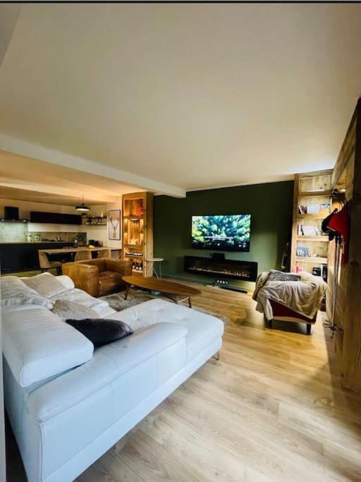 Il comprend un salon doté d'un canapé blanc et d'une télévision à écran plat. dans l'établissement Appart hyper centre Font Romeu, à Font-Romeu-Odeillo-Via