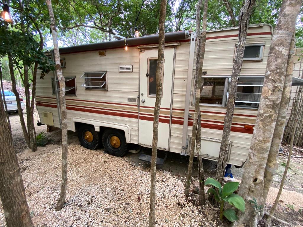 a white trailer parked in the middle of trees at MAKEX-CAMPER in Tulum