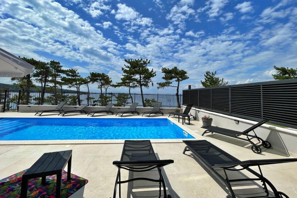 Villas Punta Silo - luxury apartments with pool في سيلو: مسبح وكراسي صالة ومسبح