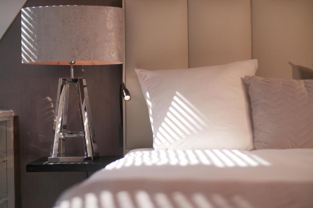 a lamp on a table next to a bed at Boutique Suites Sylt in Kampen am Roten Kliff Re-Opening Mai 2023 in Kampen