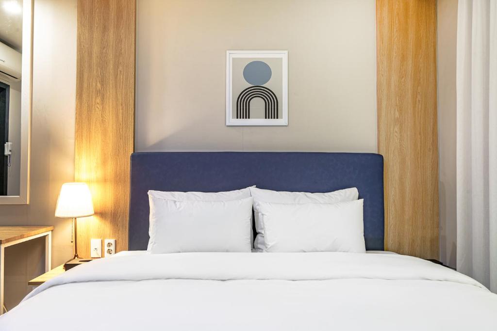 a bedroom with a large white bed with a blue headboard at Brown Dot Hotel Angang in Gyeongju