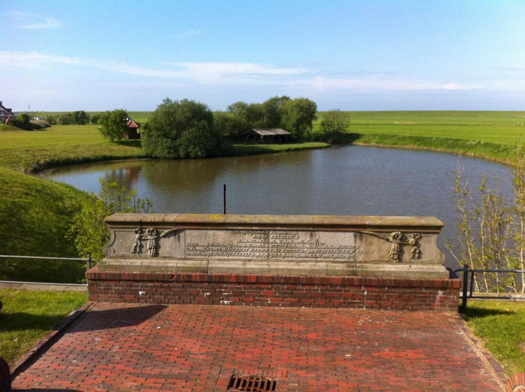 a brick wall in front of a river at Ferienhaus in Nessmersiel 20-139 in Neßmersiel