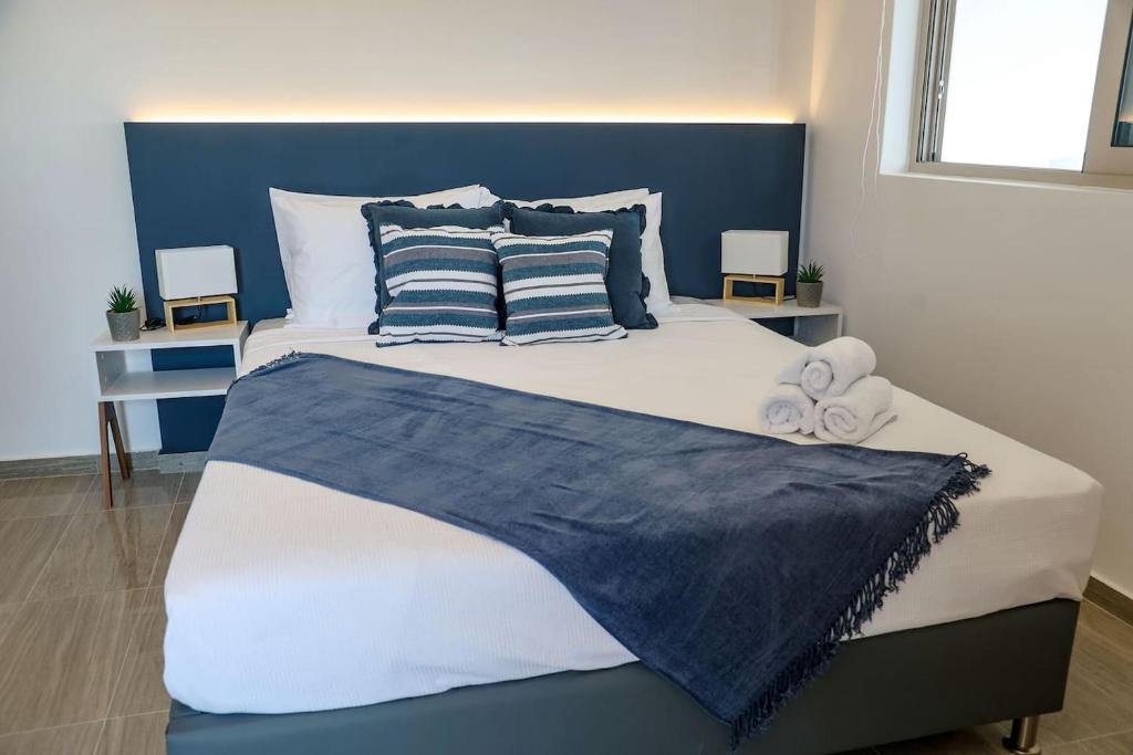 a large bed with blue and white sheets and pillows at Veranda-Ammoudara-Crete in Amoudara Herakliou