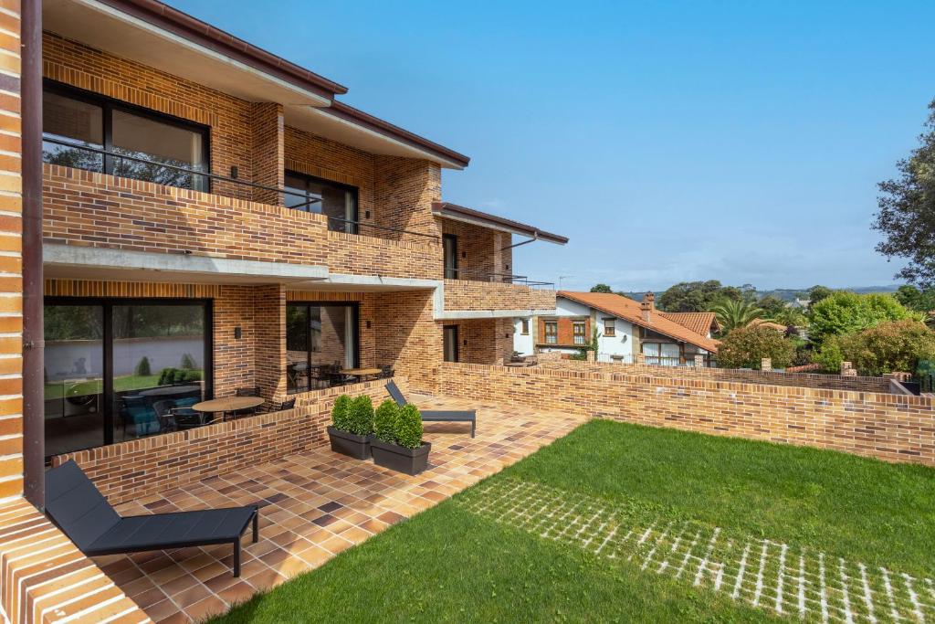 ein Backsteinhaus mit einer Terrasse und einer Liegewiese in der Unterkunft Alma Marina Apartamentos in Somo