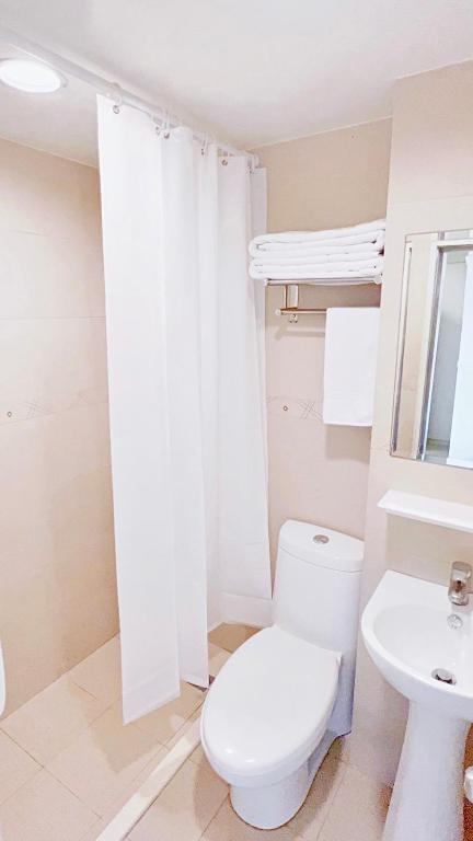 a white bathroom with a toilet and a sink at Kiwi Express Hotel - Zhong Zheng Branch in Taichung