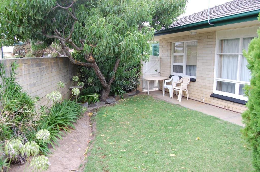 une arrière-cour avec un arbre, une table et des chaises dans l'établissement Comfortable Unit Close to the Beach, à Victor Harbor