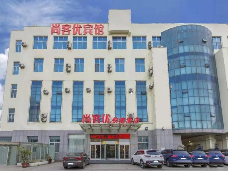un gran edificio con coches estacionados frente a él en Thank Inn Chain Hotel Exhibition Center, en Linyi