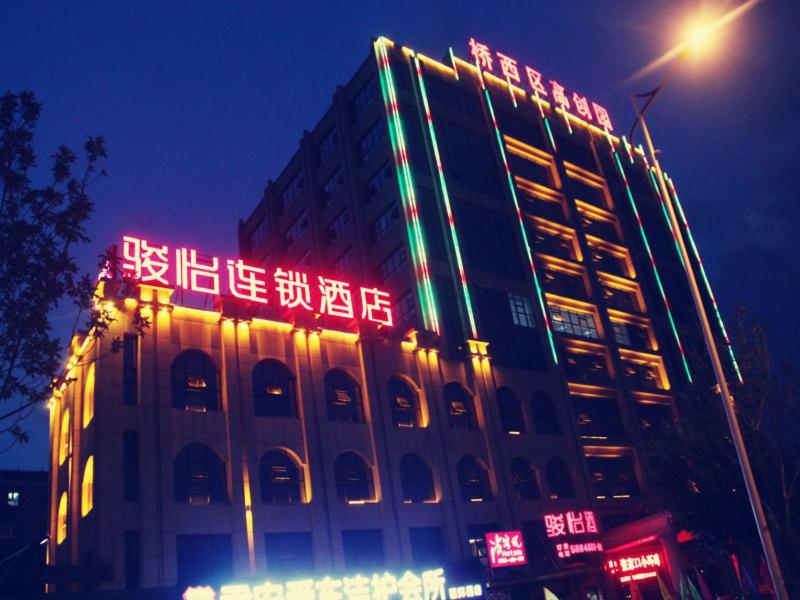a building with neon signs on the side of it at JUNYI Hotel Hebei Zhangjiakou West Bridge District Ciershan Street in Zhangjiakou