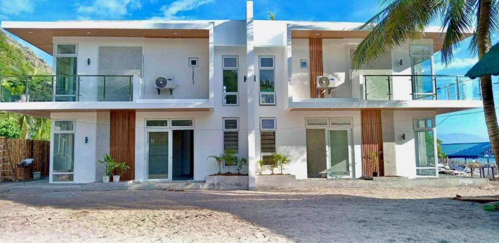 een groot wit huis aan het strand met een palmboom bij Ohana beach house - Villa #2 in Cemento