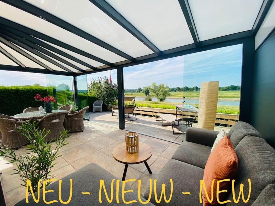 eine Terrasse mit einem Sofa und einem Tisch in der Unterkunft Ferienhaus LuxChalet VAJU IJsselView direkt am Fluss See Pool Park in Lathum