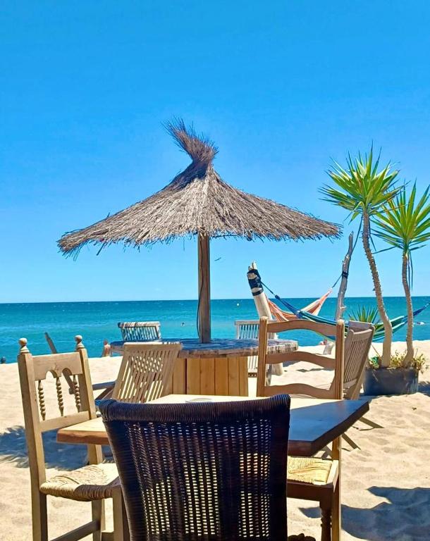 - une table avec des chaises et un parasol sur la plage dans l'établissement T3 grande terrasse bord de mer, au Barcarès