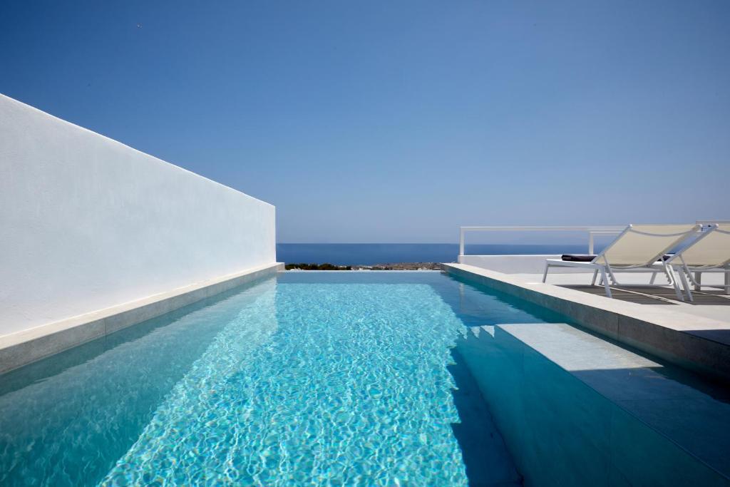 a swimming pool with chairs and the ocean in the background at Thadeos Villa with private jetted Pool in Fira