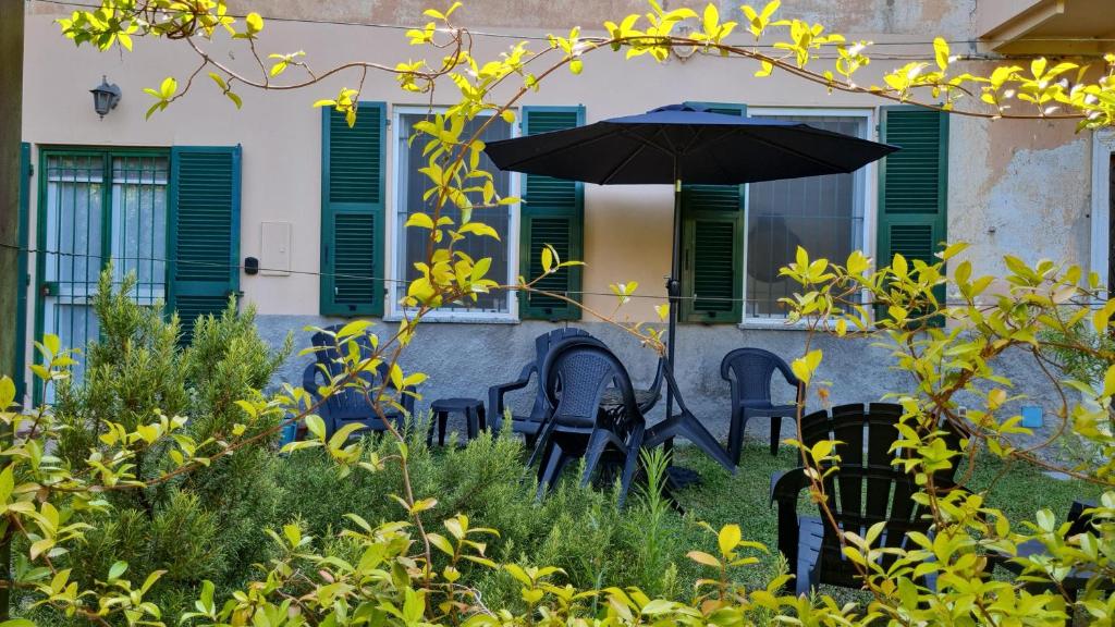 a patio with chairs and an umbrella in front of a building at Vado, in campagna in Vado Ligure