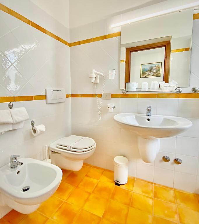 a white bathroom with a sink and a toilet at Hotel Sylesia in Letojanni