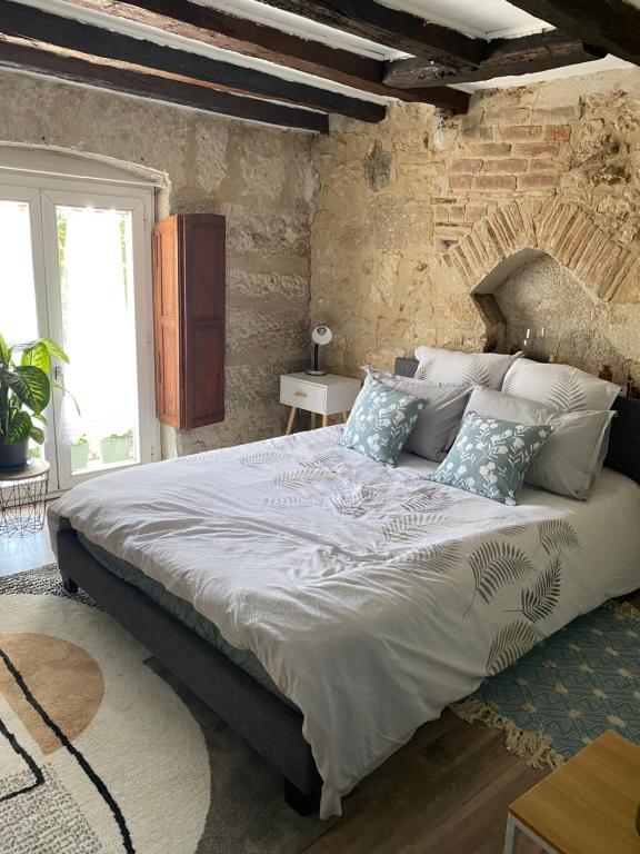 Cama grande en habitación con pared de ladrillo en LE PTIT SAINT-FRONT, en Périgueux