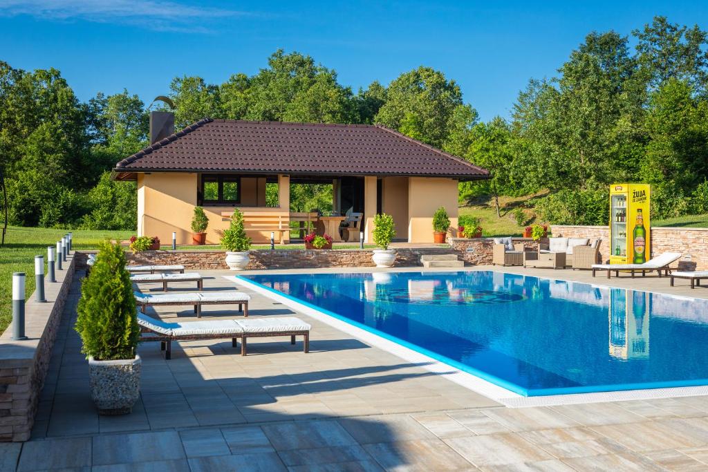 a pool with benches and a house in the background at Apartments Lucija in Slunj