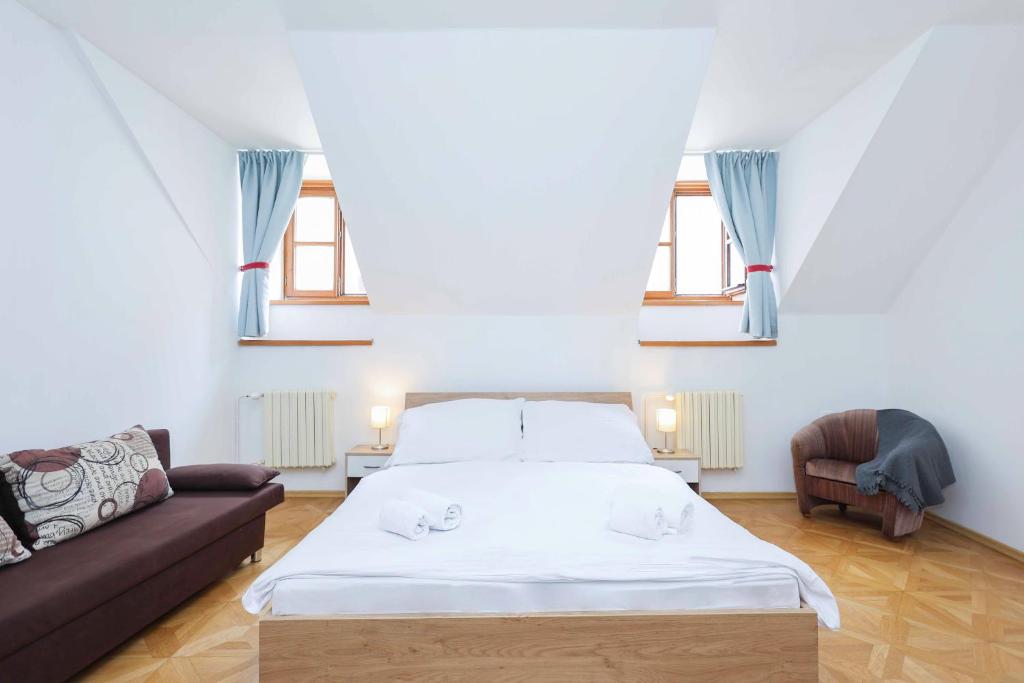 um quarto com uma cama, um sofá e janelas em Beethoven Apartments em Bratislava