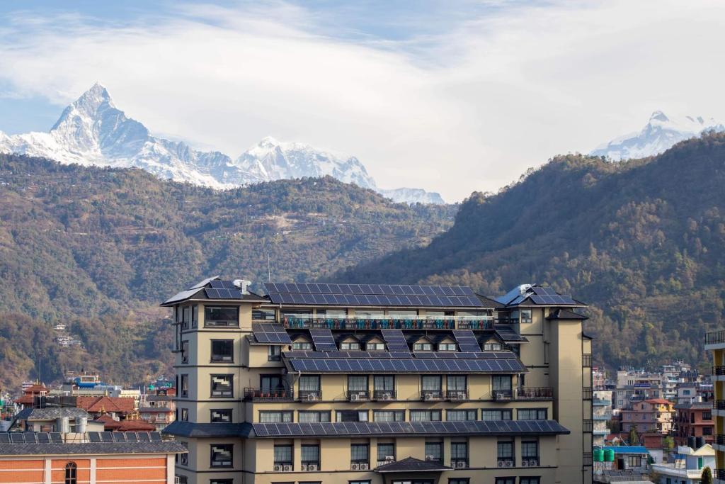 a building with snow capped mountains in the background at Hotel Sarowar in Pokhara