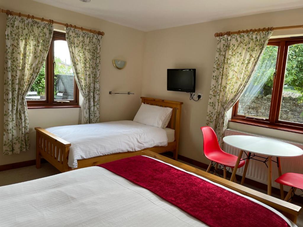 um quarto de hotel com duas camas e uma mesa e cadeiras em Sunset House B&B em Penrith