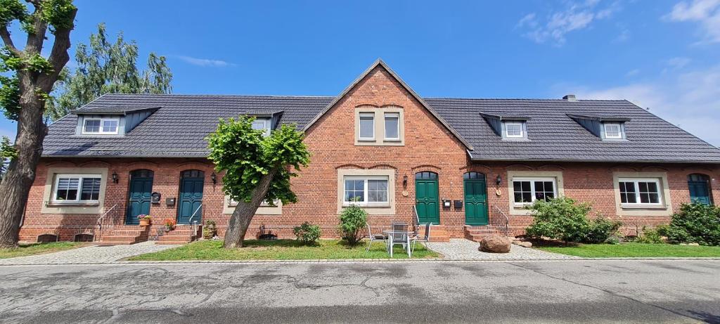 a red brick house with green shutters on a street at Zum Kranich in Luckau