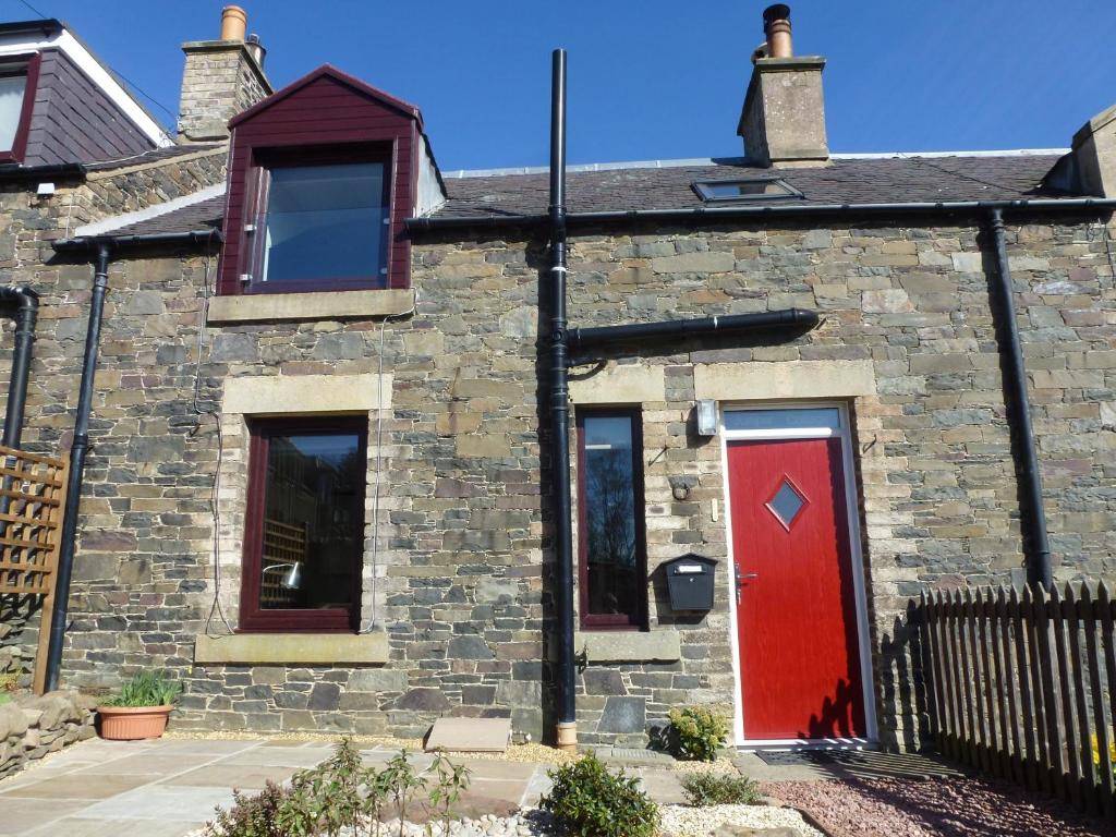 una casa de ladrillo con puerta roja en Juniper Cottage en Clovenfords