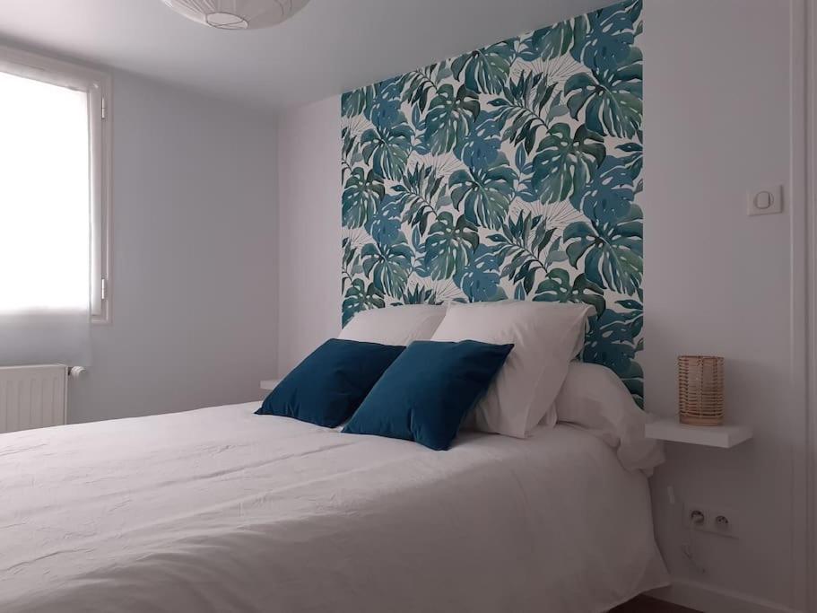 1 dormitorio con cama blanca y almohadas azules en Appartement neuf et cosy, en Cambo-les-Bains