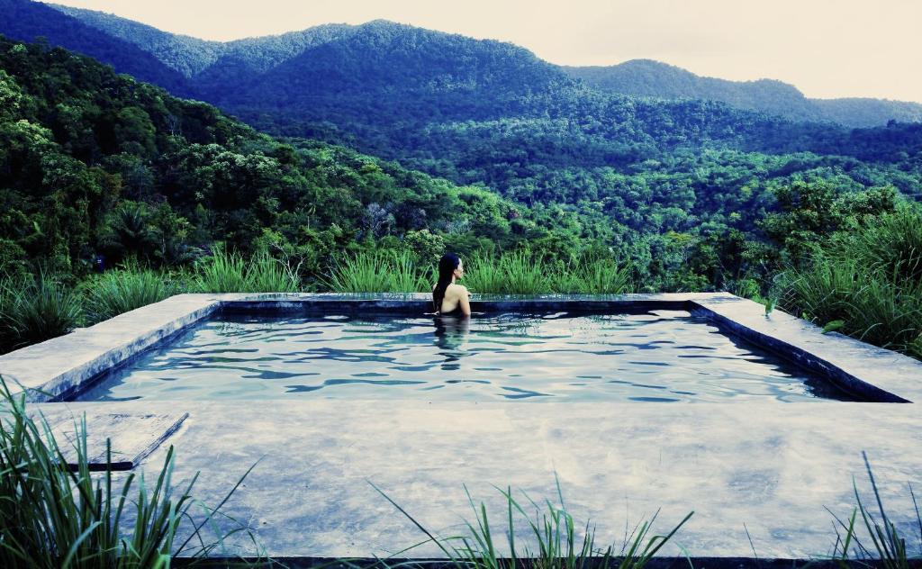 a person in a swimming pool with mountains in the background at Bukit Cottage Pak Ansel in Labuan Bajo
