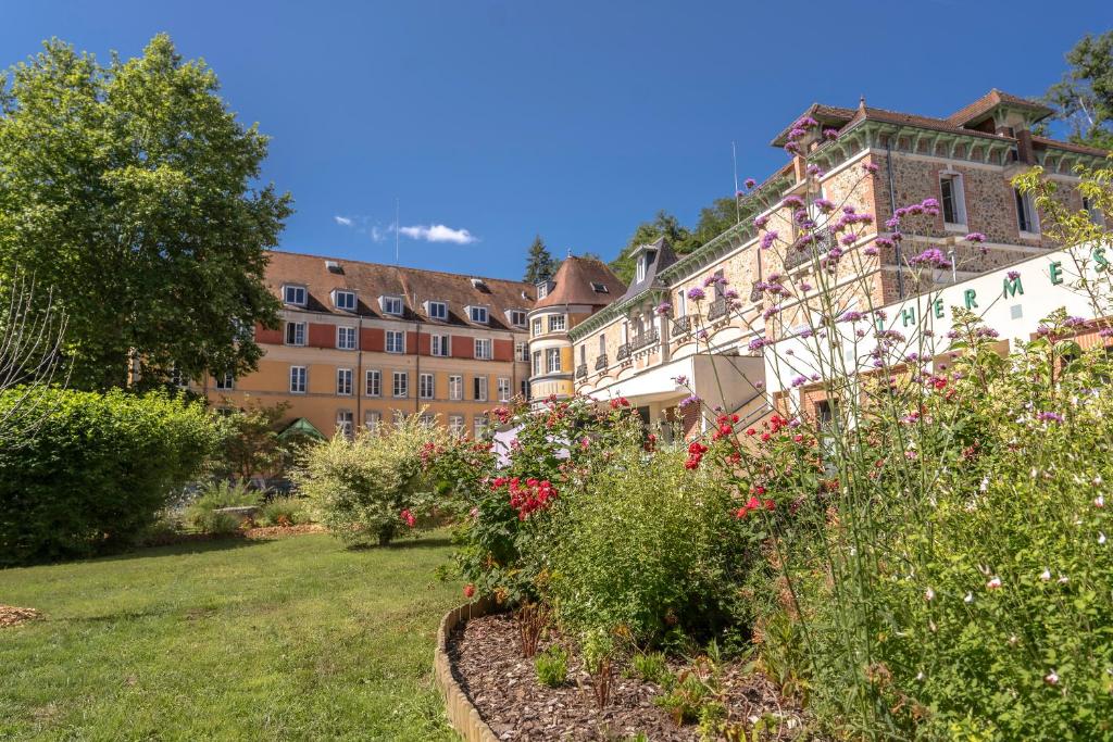un jardin fleuri devant un bâtiment dans l'établissement Le Grand Hôtel, The Originals Relais, à Évaux-les-Bains