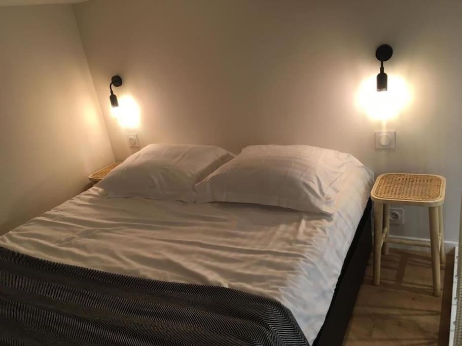 a bed in a bedroom with two lights on the wall at Vieux Nice Charmante Mezzanine in Nice