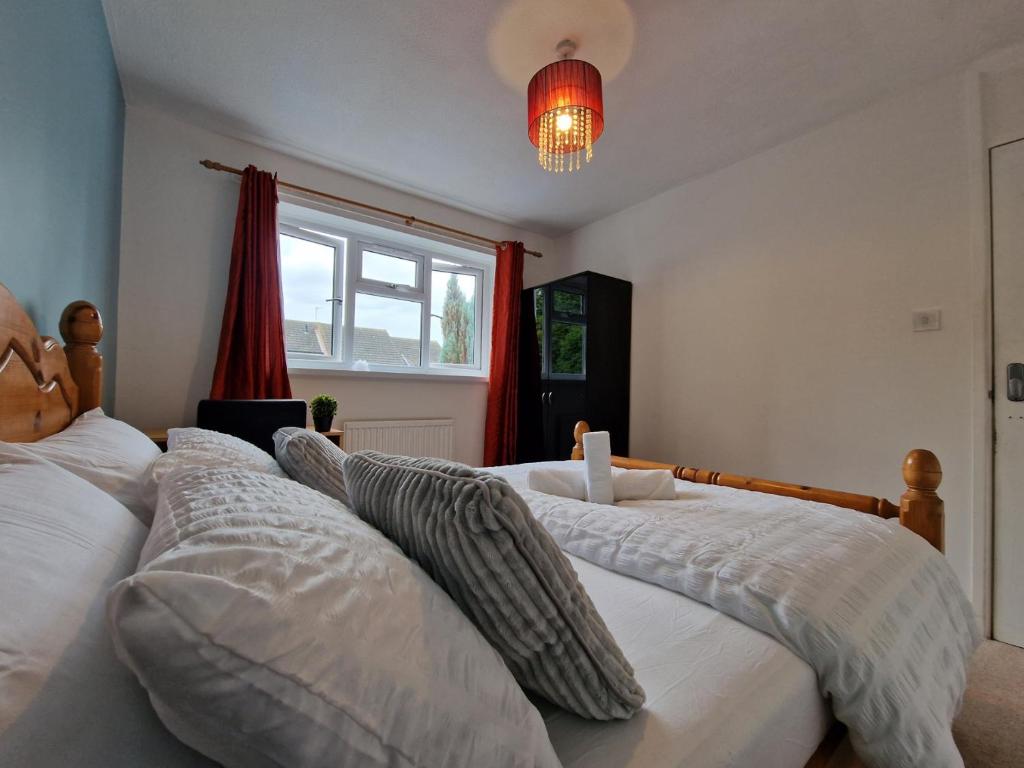 two beds in a bedroom with a red window at Nice Living Serviced Accommodations 7 in Rugby