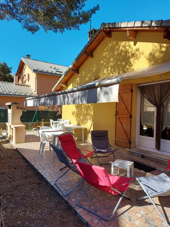 eine Terrasse mit Stühlen, einem Tisch und einem Gebäude in der Unterkunft Chalet 126 m² PRALOUP in Uvernet