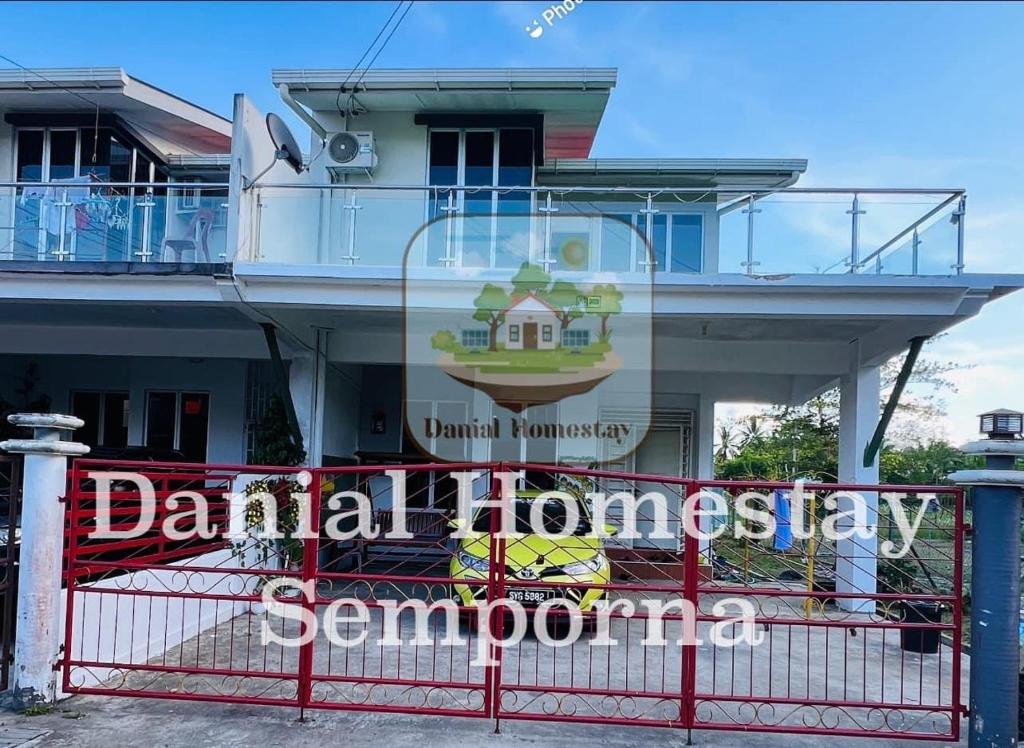 a building with a sign behind a red fence at Danial Homestay Semporna in Semporna