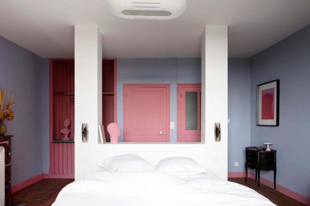 a bedroom with a white bed with a pink door at Au Petit Thouars in Thouars