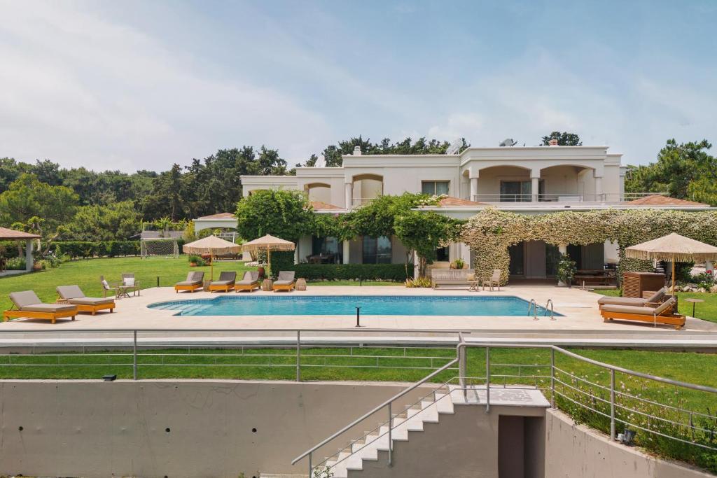 a large house with a swimming pool in front of it at Bello Blu Luxury Villa in Asgourou