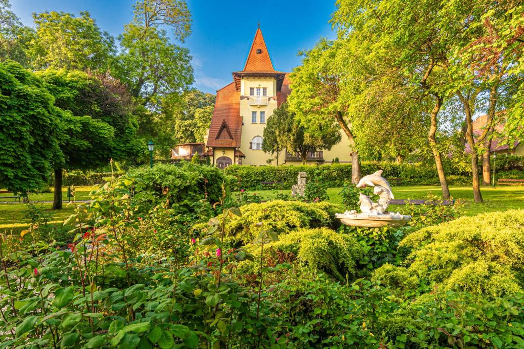 einen Garten vor einem Haus mit einer Statue in der Unterkunft Fried Kastély Hotel Simontornya in Simontornya