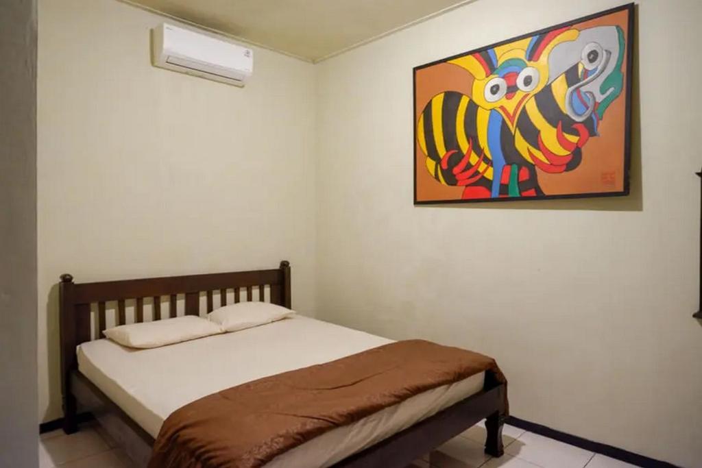 una camera da letto con un letto e un dipinto sul muro di Cakra Homestay Solo Mitra RedDoorz a Solo