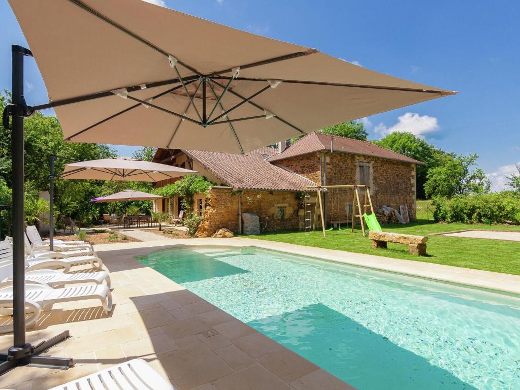einen Pool mit Sonnenschirm neben einem Haus in der Unterkunft Spacious farmhouse with private heated pool in a rustic garden in Nantheuil