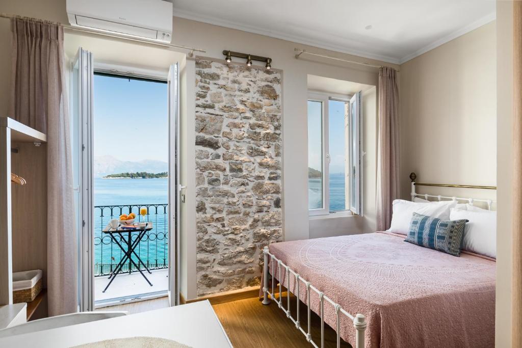 Schlafzimmer mit einem Bett und Blick auf das Wasser in der Unterkunft Fotiadis Family Luxury Suites by Konnect in Korfu-Stadt