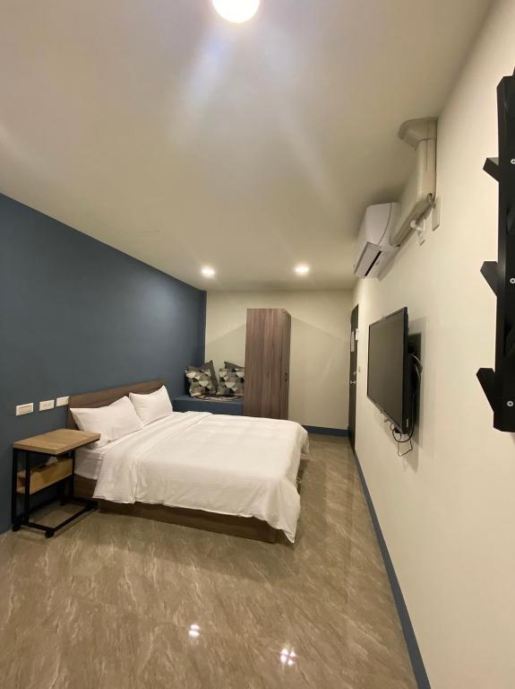 una camera da letto con un letto bianco e una televisione di 亞士密民宿 a Puli