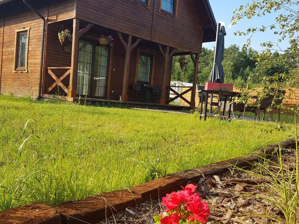 a log cabin with a flower in the yard at Wooden Holiday Home in Skrzynia with Terrace in Osiek