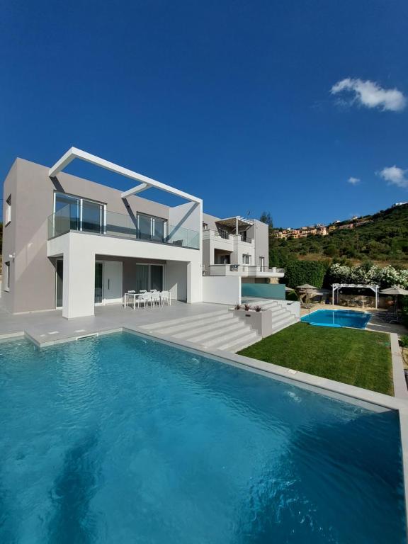 une villa avec une piscine en face d'une maison dans l'établissement Oceana Suites, à Georgioúpoli