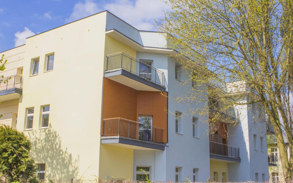 an apartment building with balconies and a tree at Kompleks Hotelowo-Rekreacyjny “Kasztelanka” in Ciechocinek