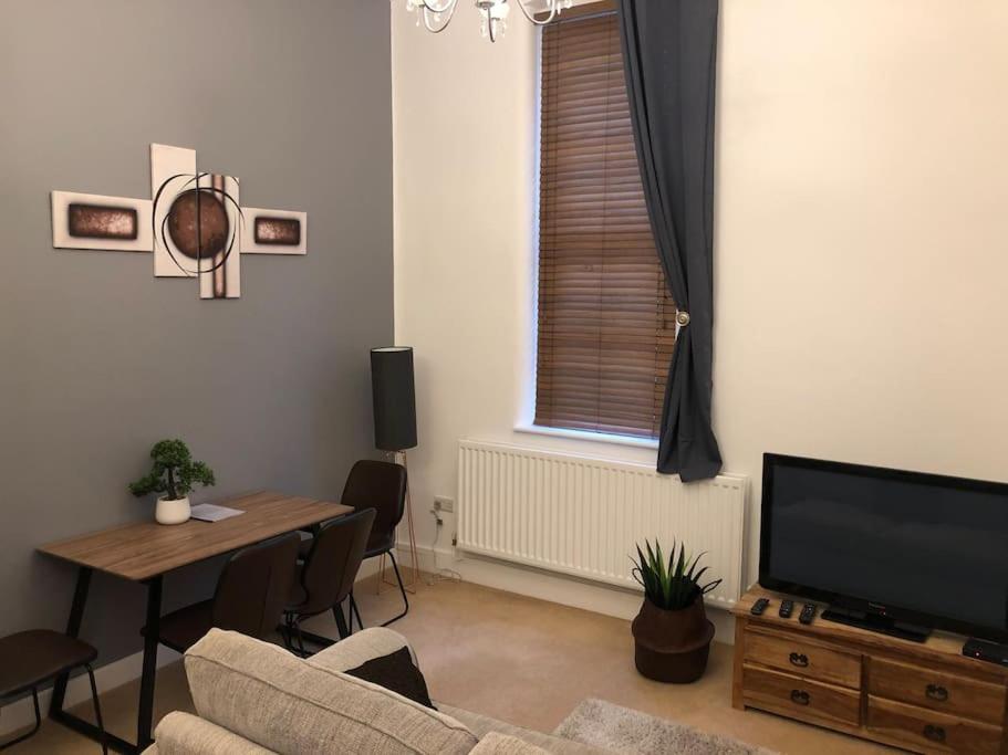 a living room with a couch and a table and a television at Fusilier apartment wrexham city in Wrexham