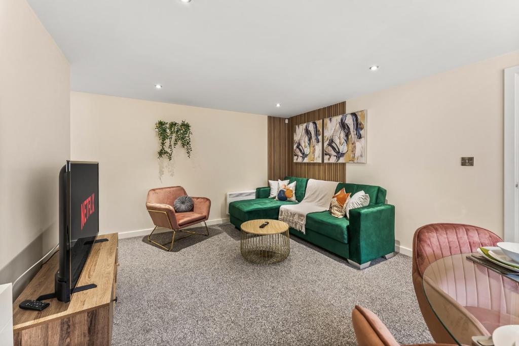 a living room with a green couch and a tv at Spacious & Modern 2 Bedroom Flat in Sheffield in Sheffield